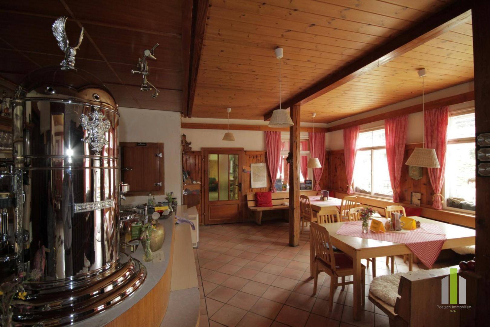 Rustikaler Speisesaal mit Holztischen, Bänken und einem großen Ofen, ideal für gesellige Runden.