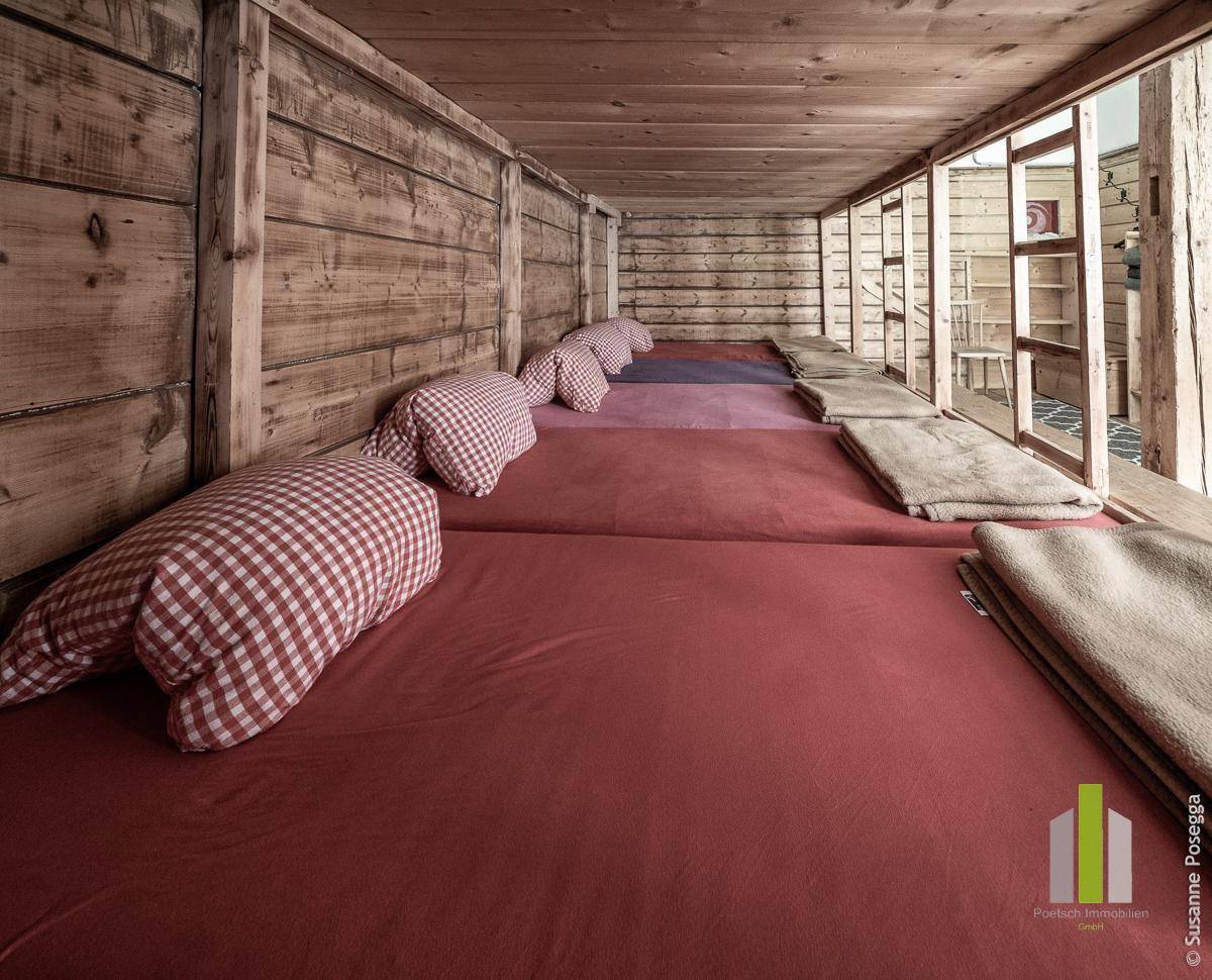 Gemütlicher Schlafbereich mit mehreren Betten und Holzwänden, ideal für Gruppenunterkünfte.