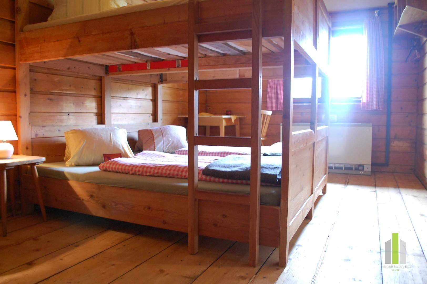 Gemütliches Schlafzimmer mit Etagenbett und Holzwänden, durchflutet von natürlichem Licht und rustikalem Charme.