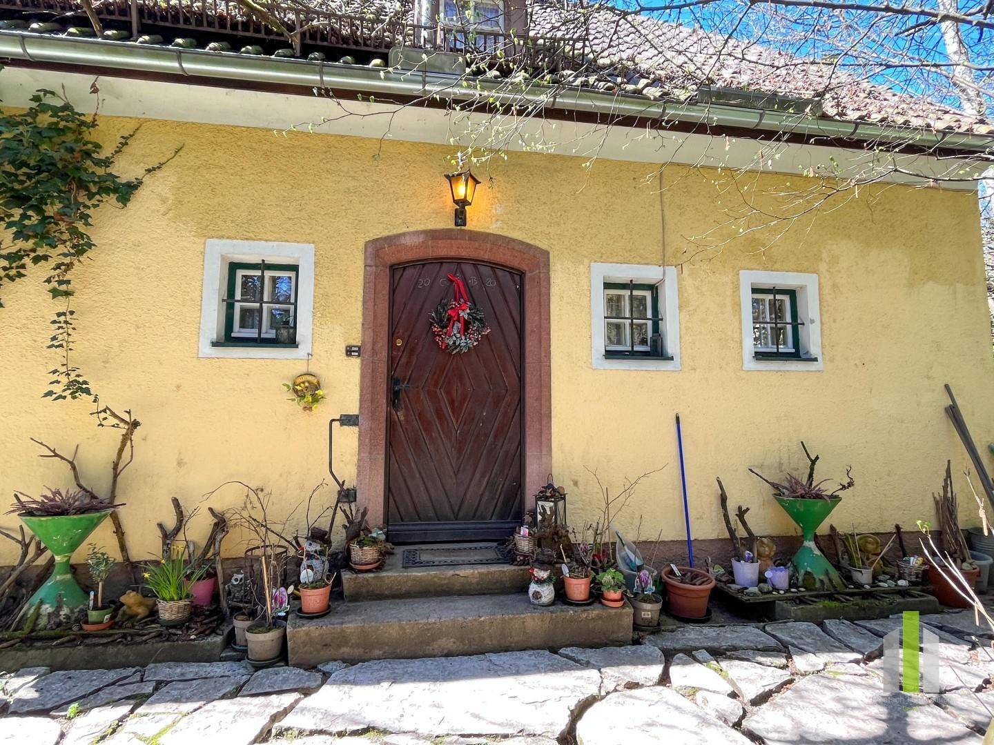 Traditioneller Eingangsbereich des gelben Hauses mit Holztür und Steinfliesenweg.