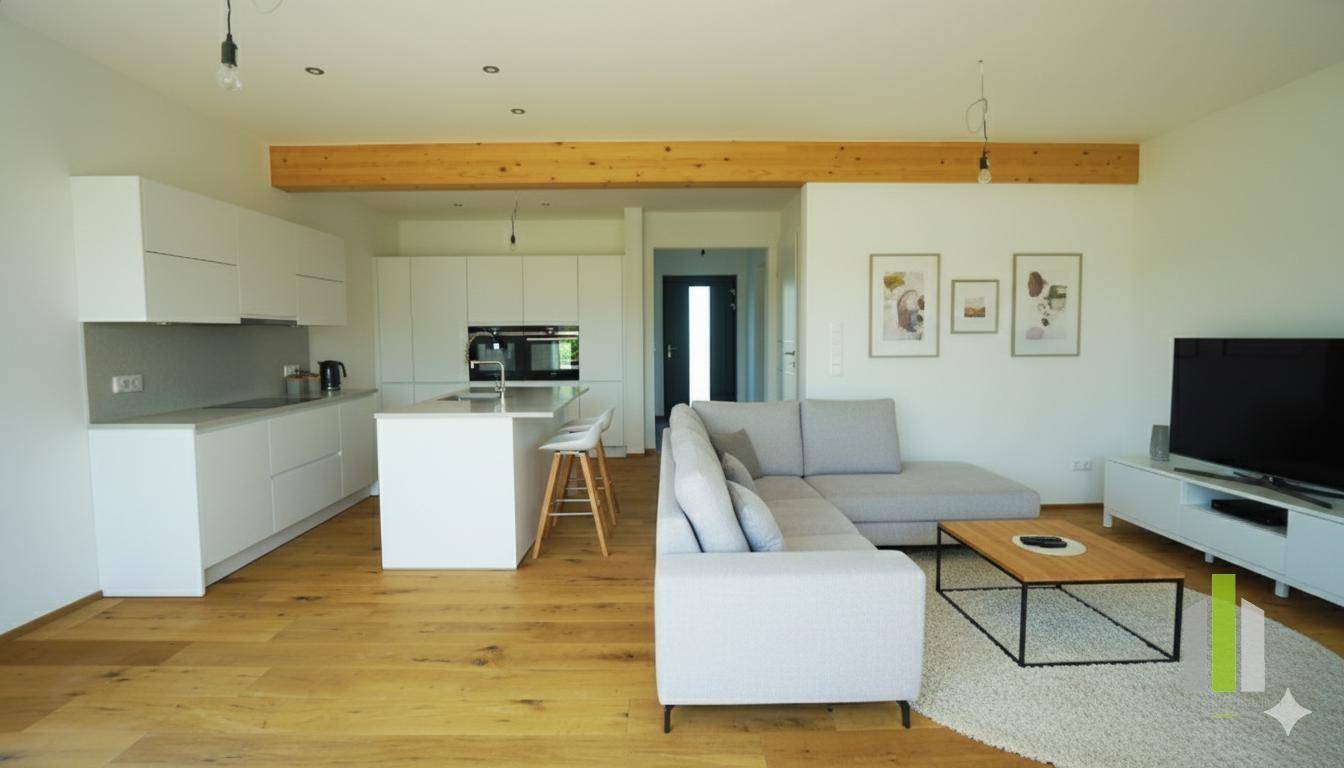 Heller offener Wohnbereich mit moderner Einbauküche, Kücheninsel und gemütlichem Sofa.