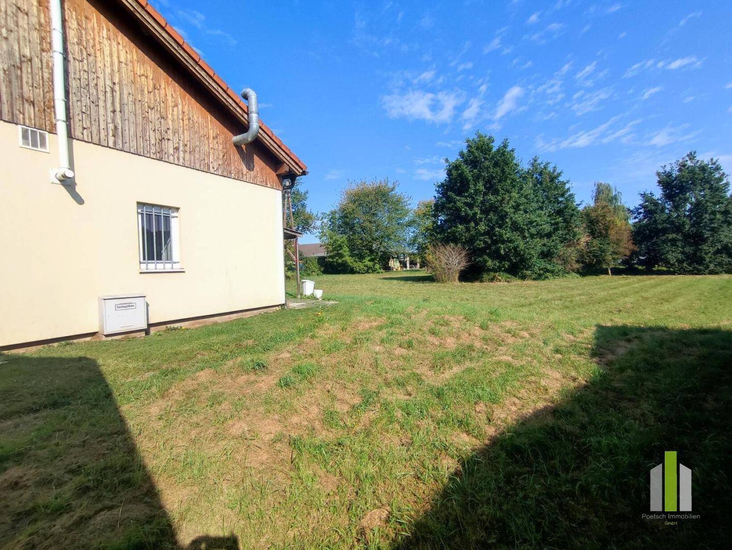 Großer, gepflegter Gartenbereich neben dem Gebäude unter strahlend blauem Himmel.