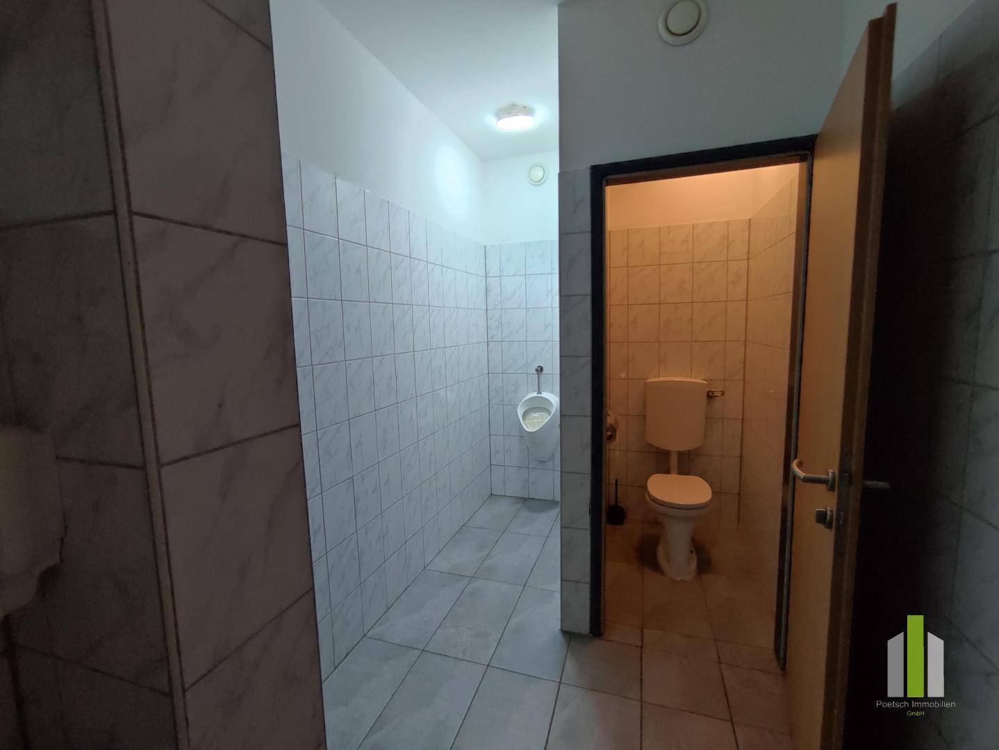 Mehrere Toilettenkabinen mit Urinal und WC, alle gefliest und in gutem Zustand.