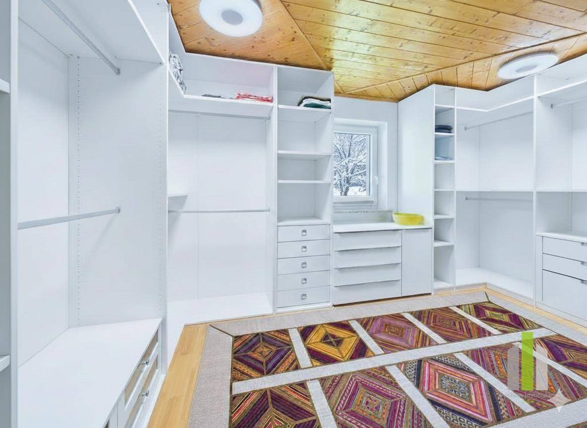 Geräumiger begehbarer Kleiderschrank mit vielen Ablagemöglichkeiten und Holzdecke.