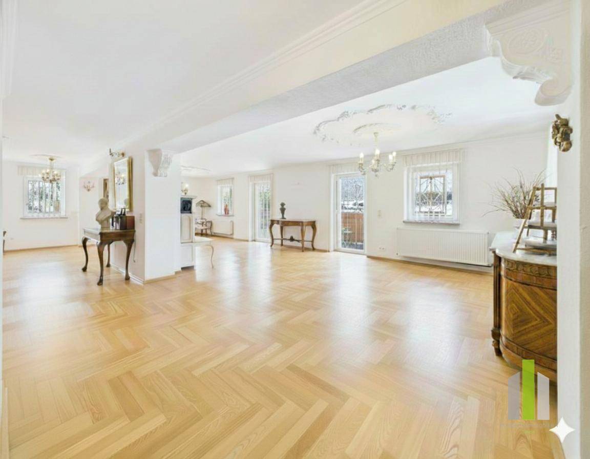 Geräumiges Wohnzimmer mit hellem Fischgrätparkett, Stuckdecken und Zugang zu einem Balkon.