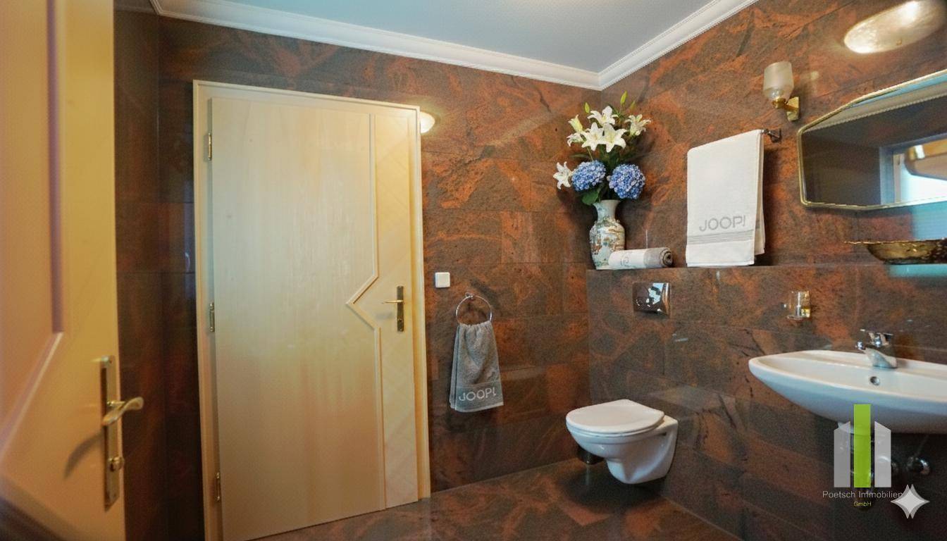 Modernes Gäste-WC mit dunklen Fliesen, wandmontierter Toilette und Einzelwaschbecken.