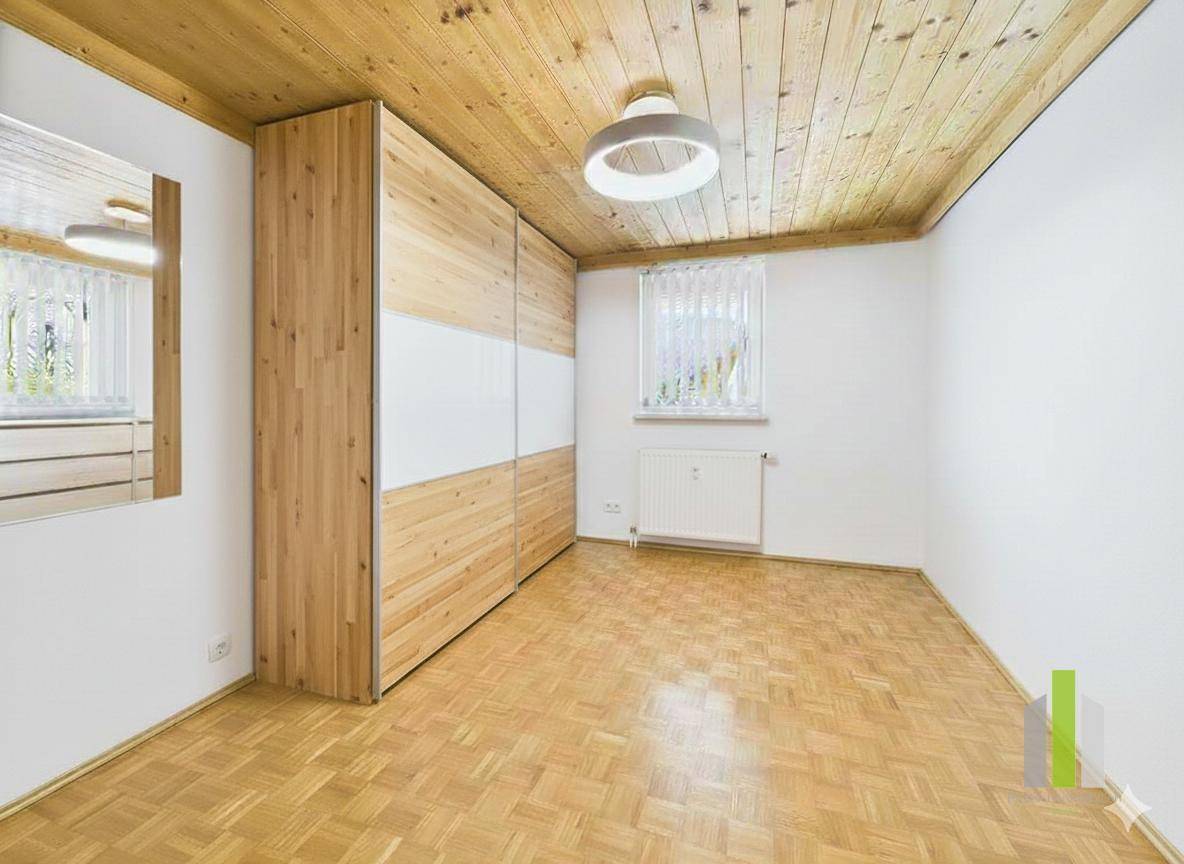 Schlafzimmer mit Holzdecke, Parkettboden und einem großen Einbauschrank.