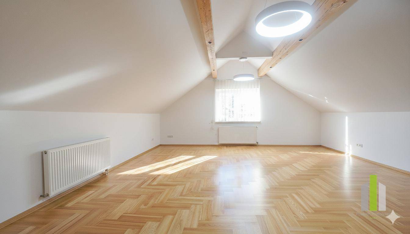 Helles Dachgeschosszimmer mit sichtbaren Holzbalken, Parkettboden und schrägen Wänden.