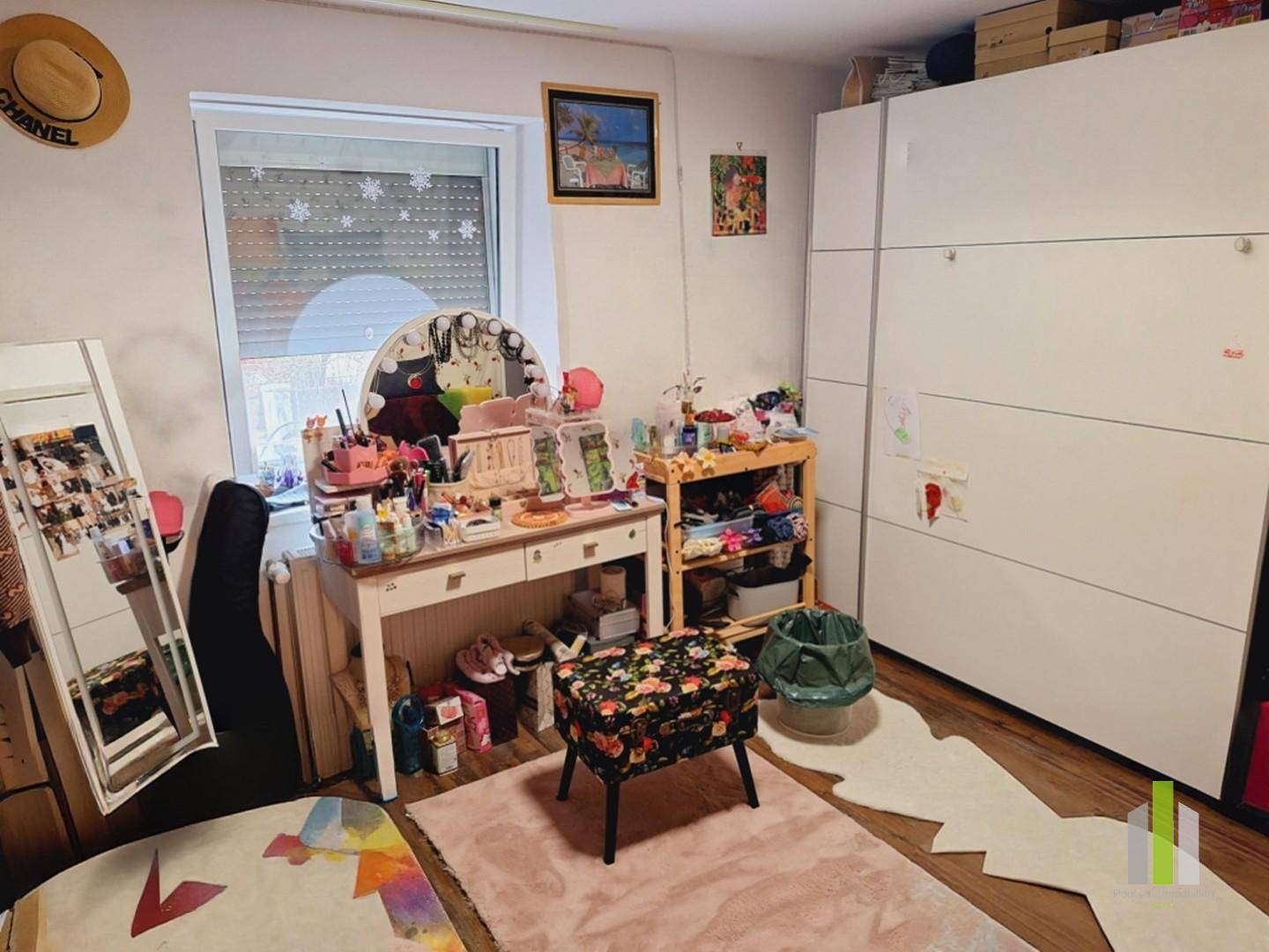 Helles Schlafzimmer mit einem Schminktisch, großem Kleiderschrank und Fenster.