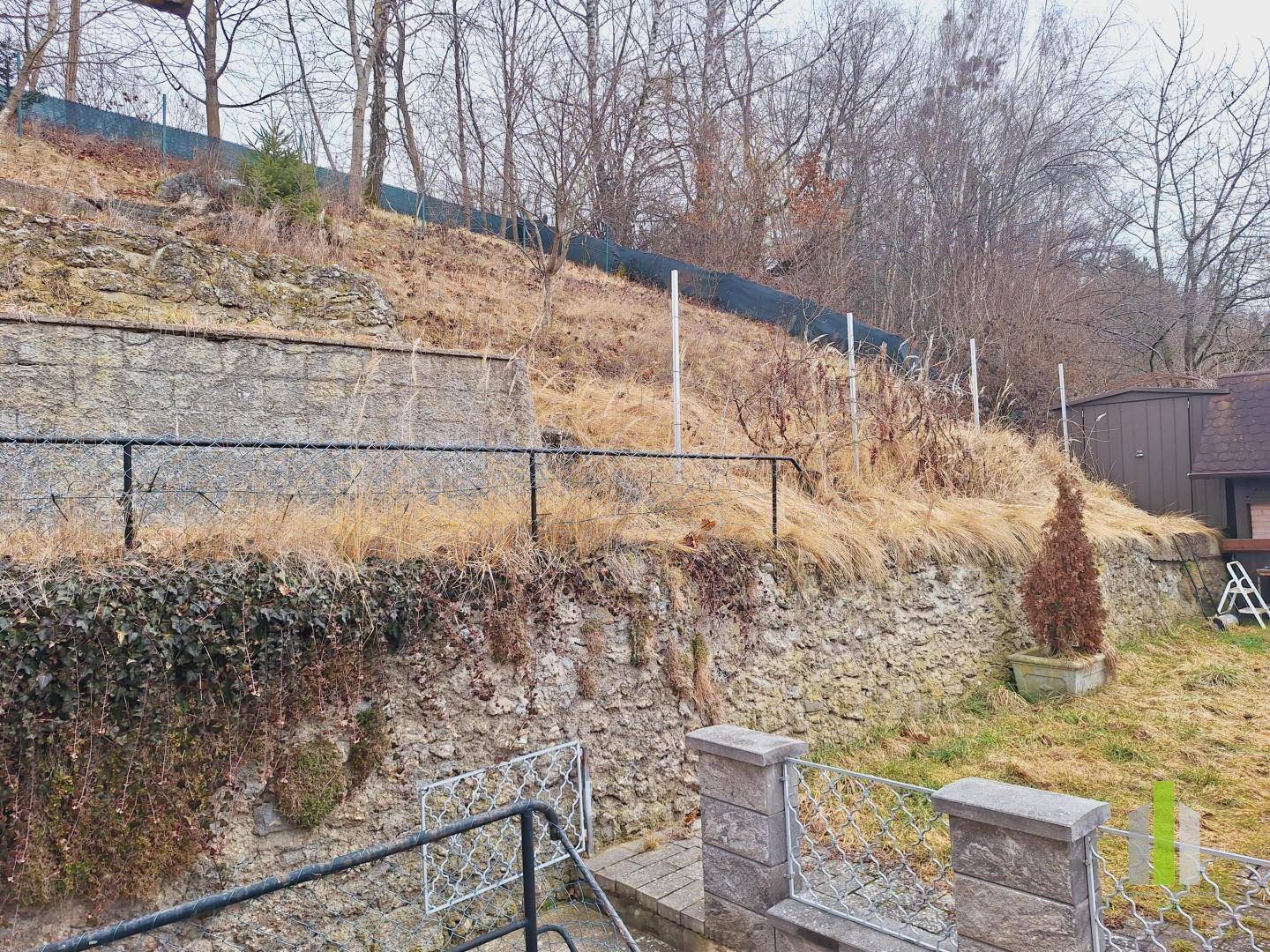 Naturbelassener Hang hinter dem Grundstück mit Trockenmauern und spärlicher Vegetation.