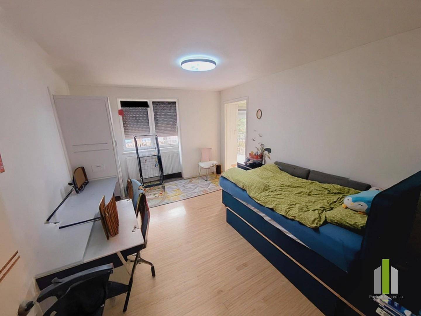 Helles Kinderzimmer mit Bett, Schreibtisch und Fenster, das viel Tageslicht hereinlässt.