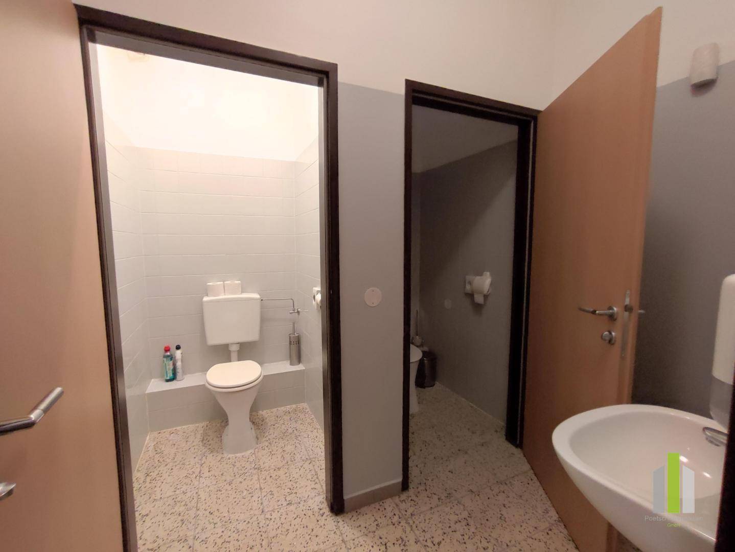 Toilettenbereich mit WC, Waschbecken und Fliesenboden, in einem gepflegten Zustand.