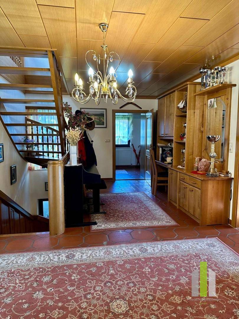 Heller Eingangsbereich mit Holztreppe, Teppichen und traditionellen Möbeln.