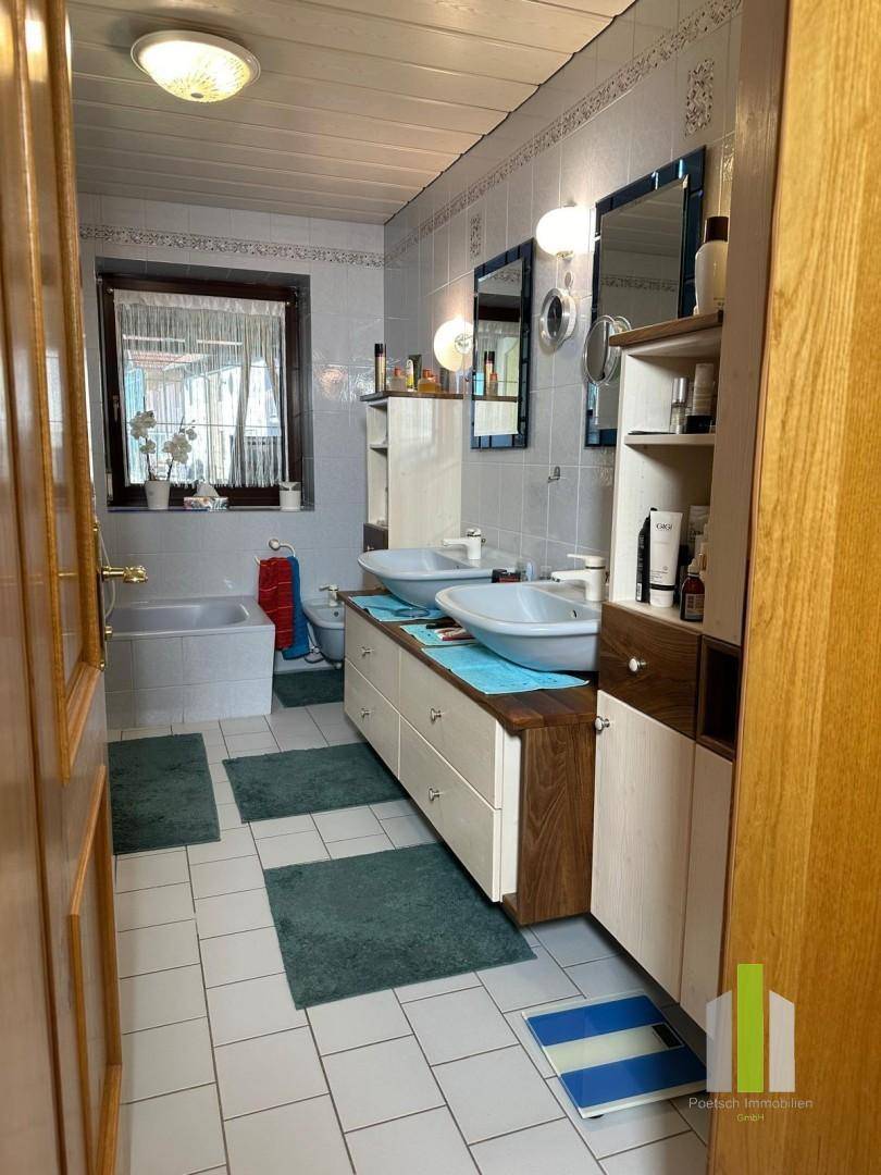 Geräumiges Badezimmer mit Doppelwaschbecken, Badewanne und Fenster.