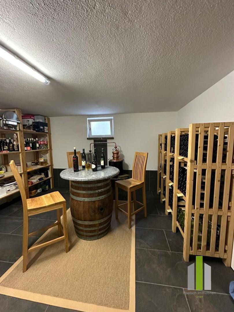 Rustikaler Weinkeller mit Holzregalen, Stehtisch und Weinfässern.