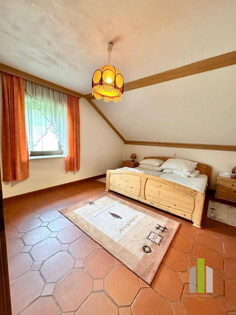Gemütliches Schlafzimmer im Dachgeschoss mit Holzbalken, Terrakottaboden und rustikalem Charme.