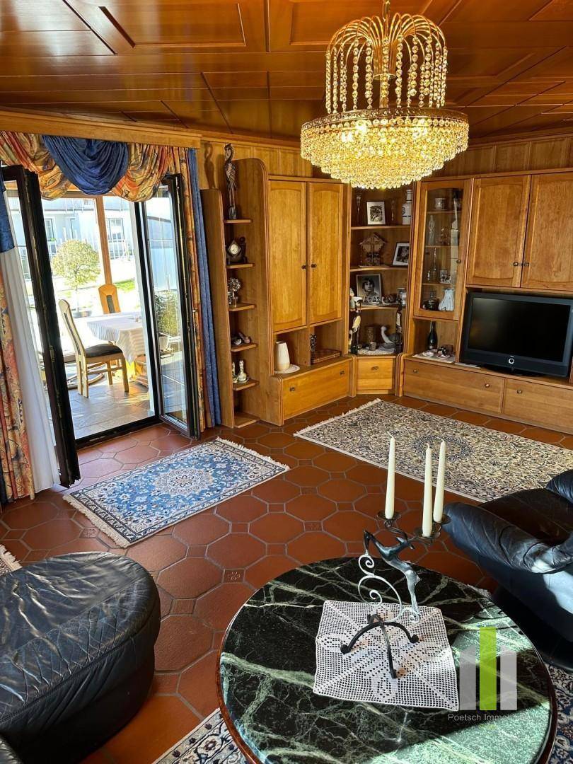 Gemütliches Wohnzimmer mit traditionellen Holzmöbeln, Kronleuchter und Zugang zur Terrasse.