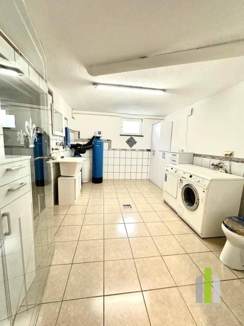 Großer Hauswirtschaftsraum mit Waschmaschine, Spülbecken und Wasseraufbereitungsanlage.