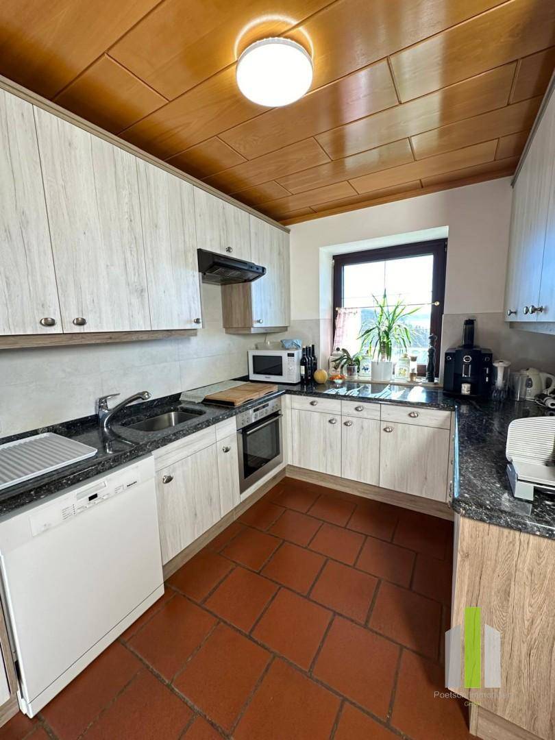 Funktionale Küche mit hellen Holzfronten, Granitarbeitsplatte und Fenster.