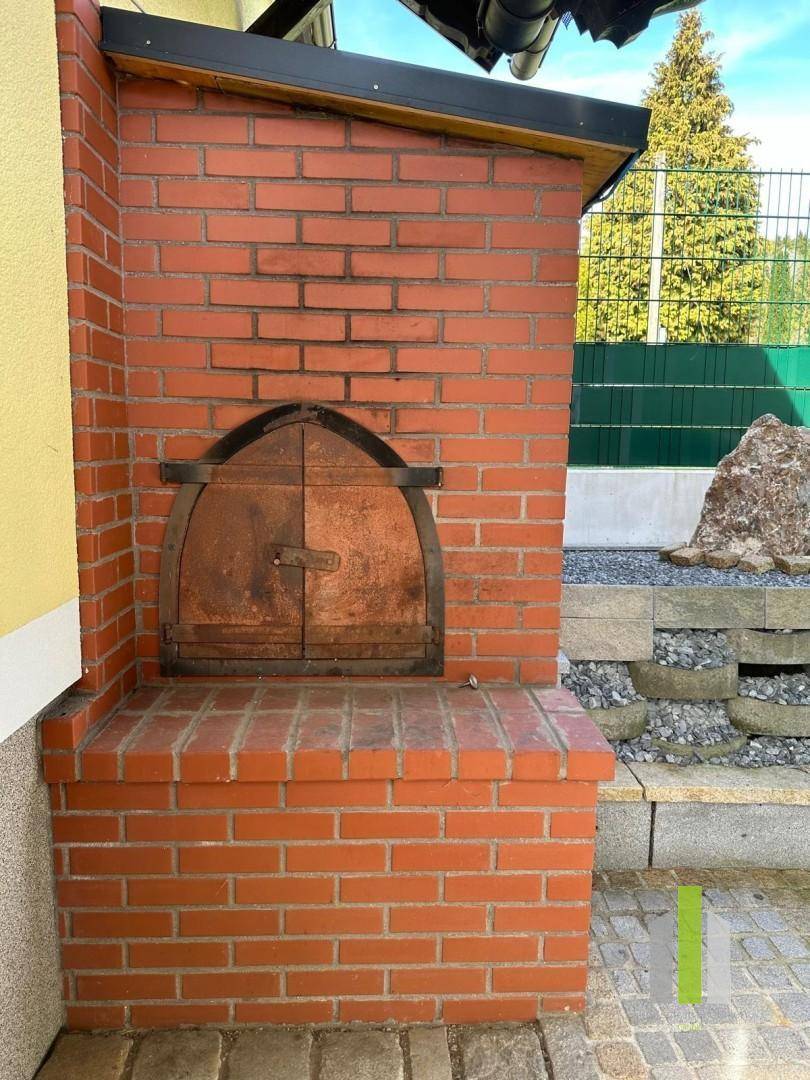Rustikaler gemauerter Außenofen mit Holzlager für gemütliche Abende im Freien.