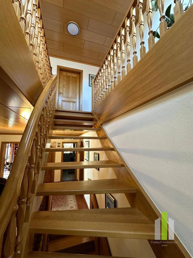 Elegante Holztreppe mit geschnitztem Geländer und Holzdecke.