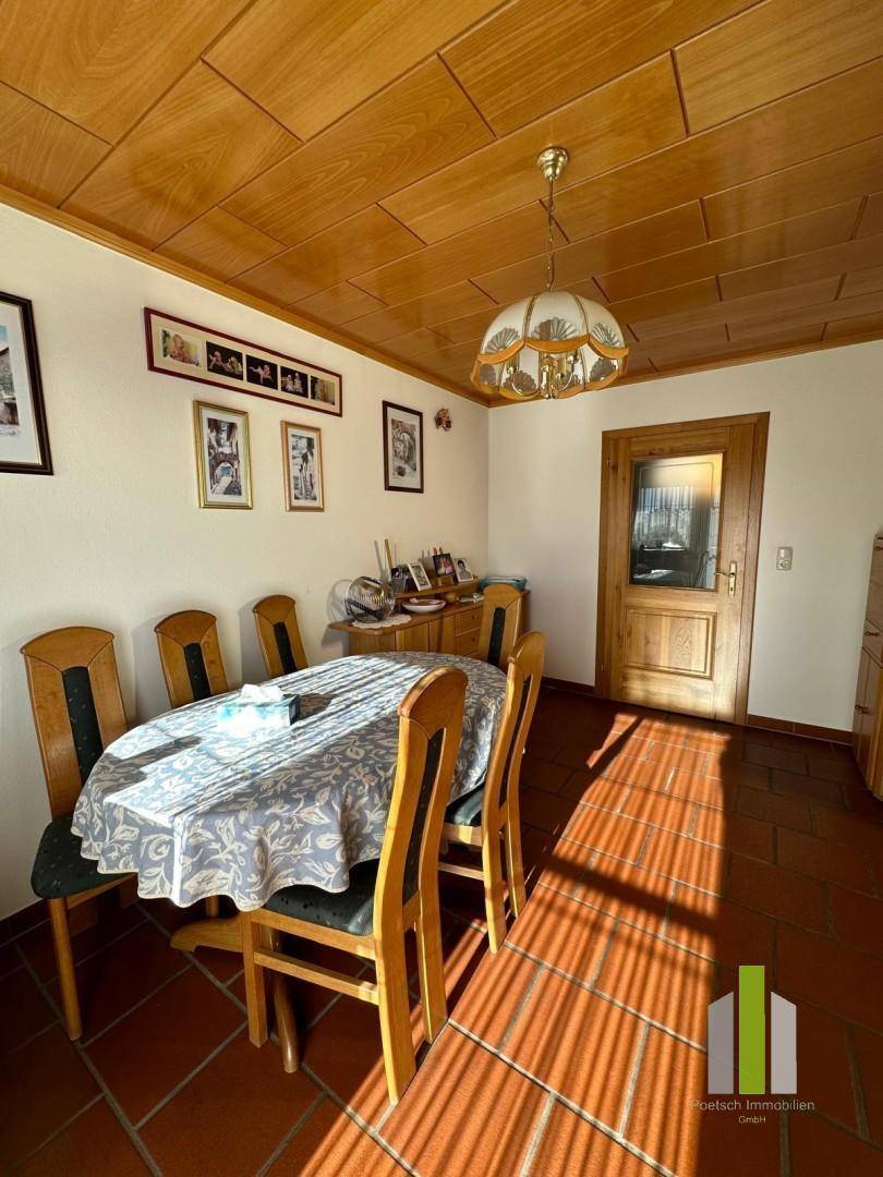 Gemütliches Esszimmer mit Holztisch, Stühlen und traditioneller Holzdecke.