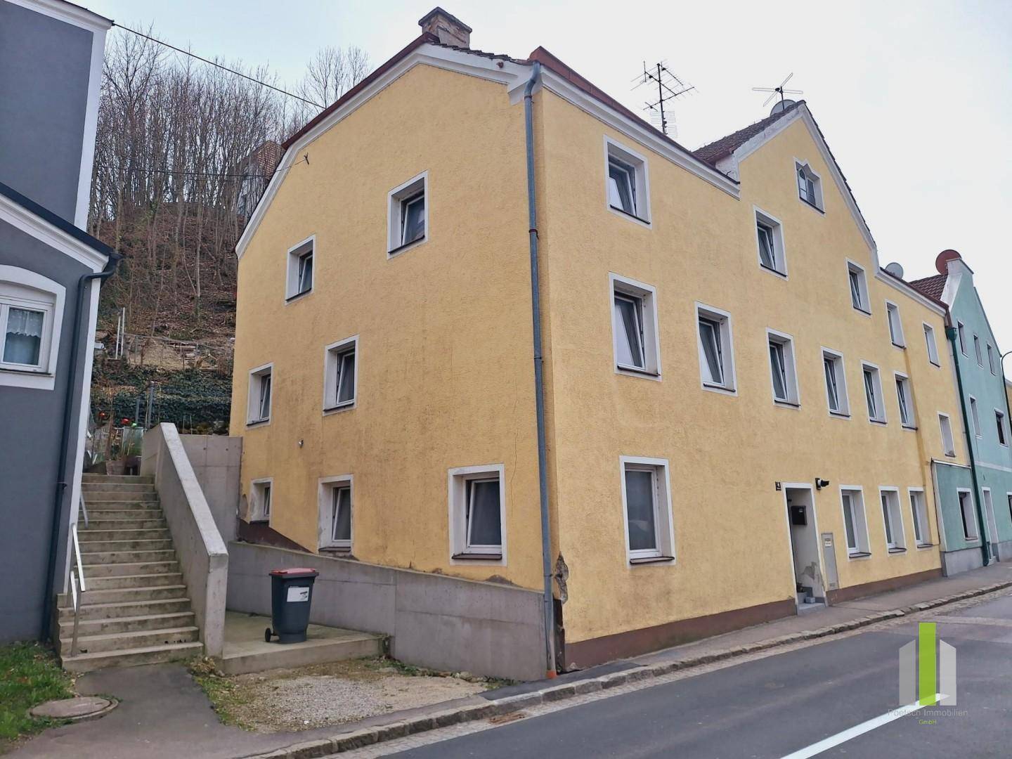 Seitenansicht des gelben Gebäudes mit Außentreppe, die einen Hang hinaufführt.