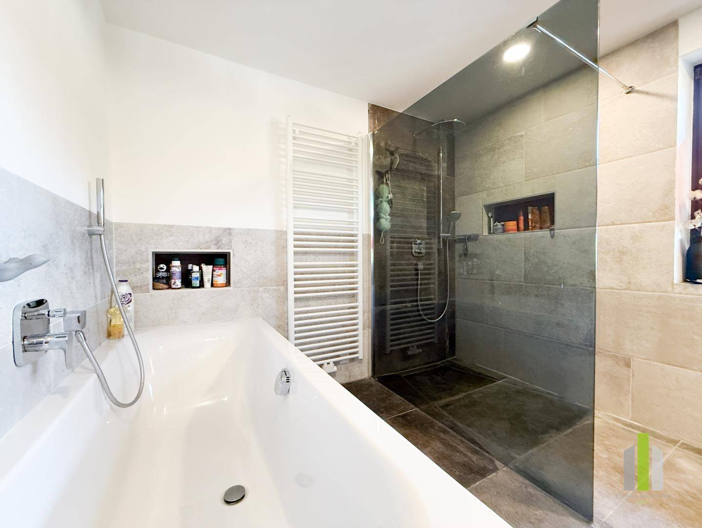Modernes Badezimmer mit Badewanne, begehbarer Dusche und beheiztem Handtuchhalter.