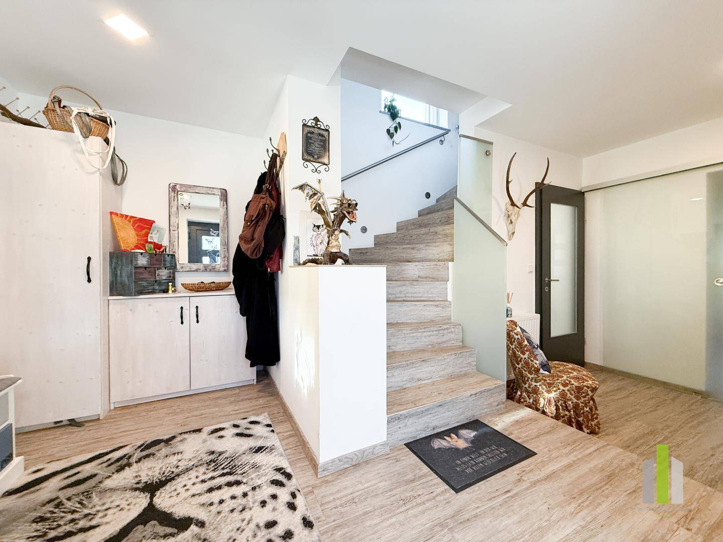 Heller Eingangsbereich mit Holztreppe, Garderobe und dekorativen Elementen.