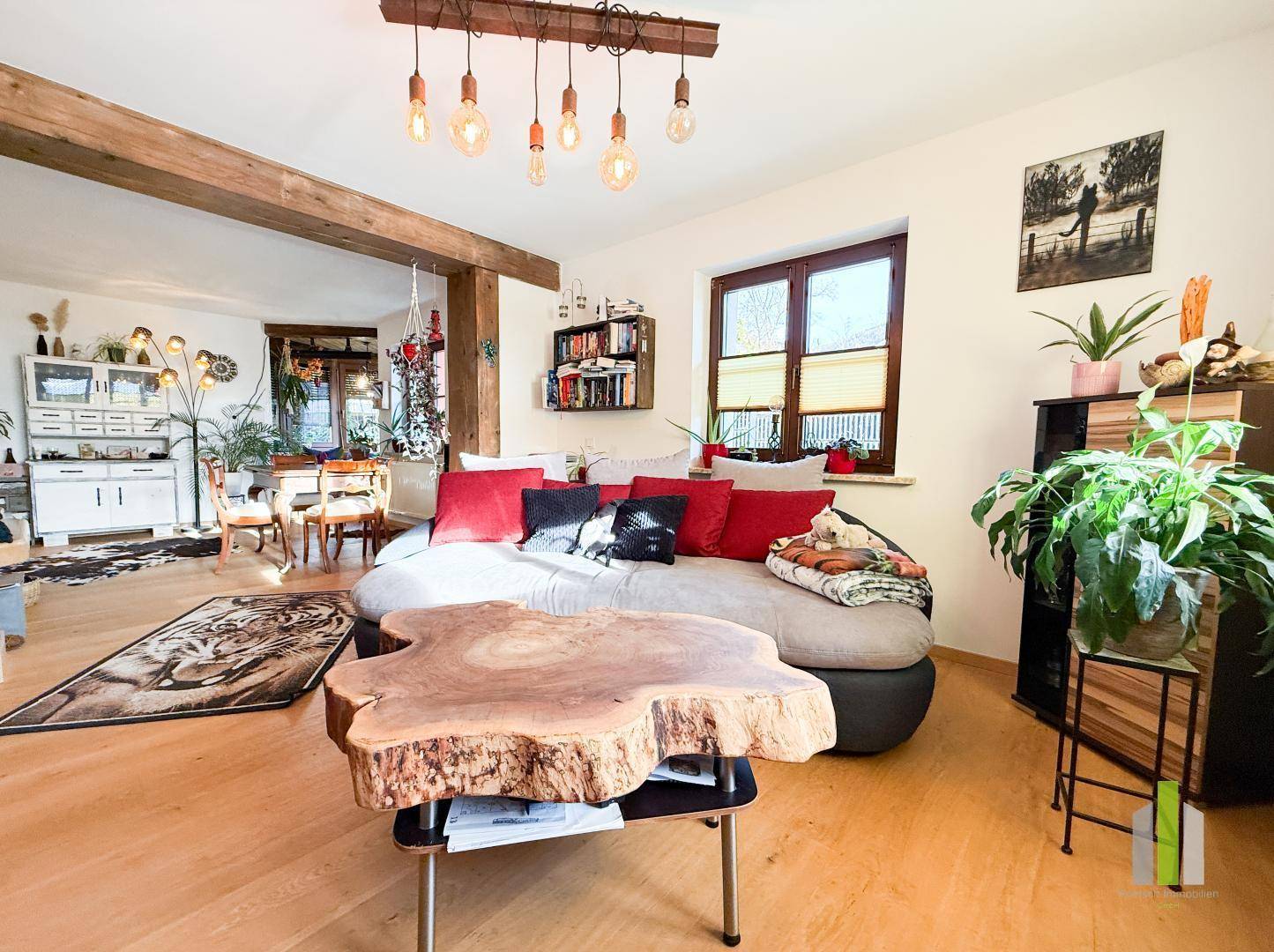 Gemütliches Wohnzimmer mit großem Sofa, Holzboden und rustikalen Holzbalken, hell und einladend.