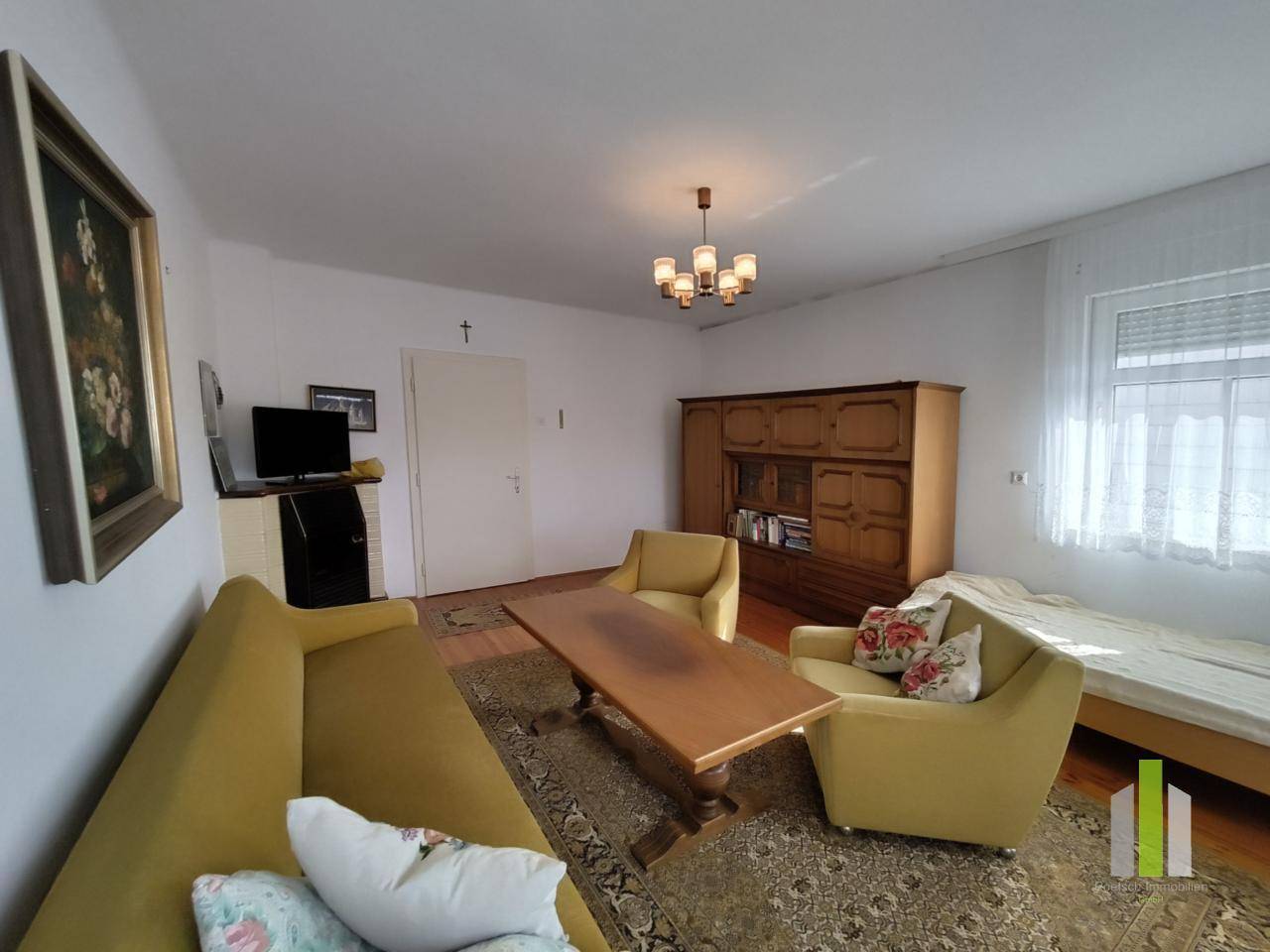 Gemütliches Wohnzimmer mit traditionellen Möbeln, Teppich und Fernseher.