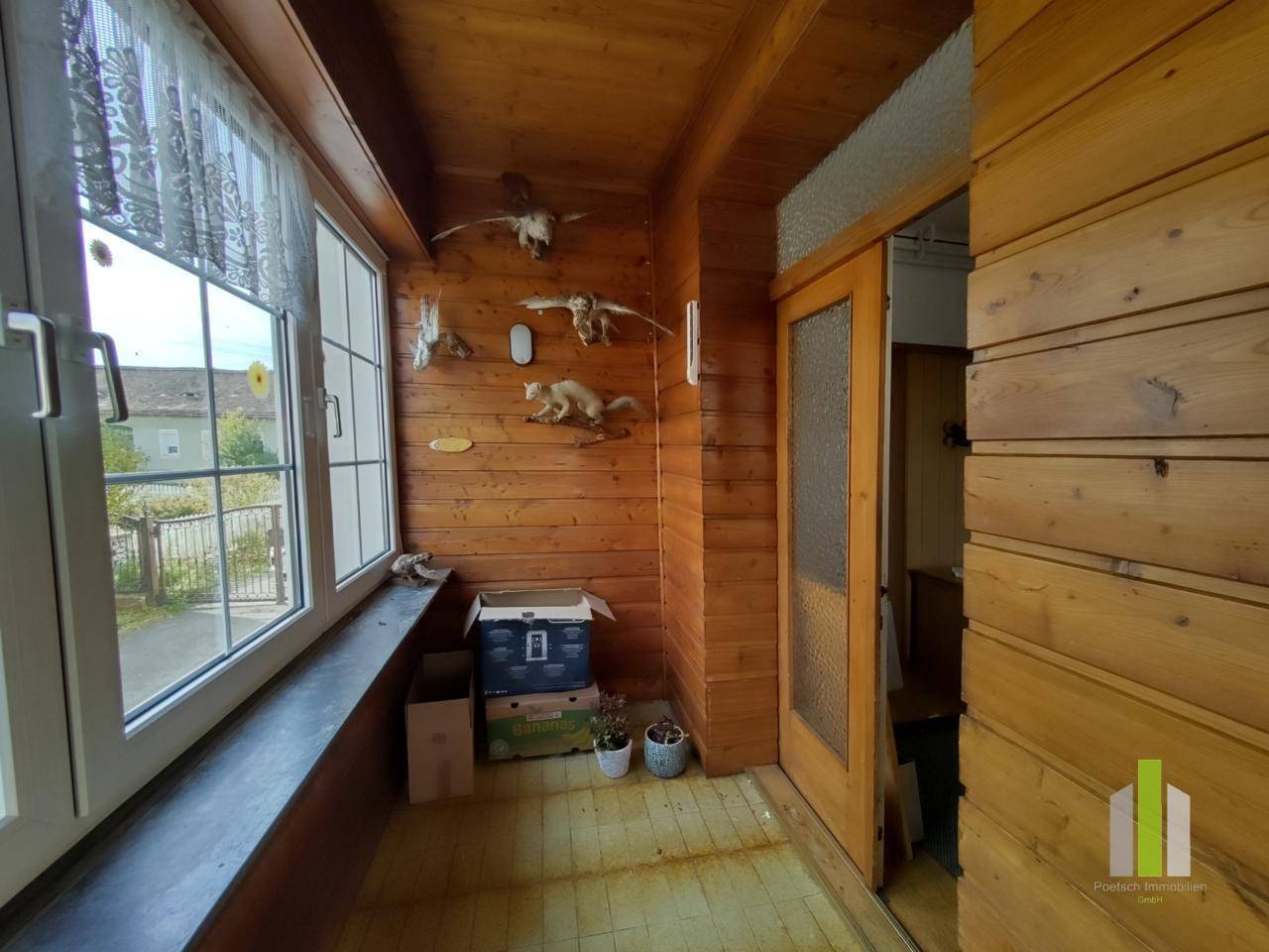 Rustikaler Eingangsbereich mit Holzvertäfelung, Fenstern und traditioneller Dekoration.