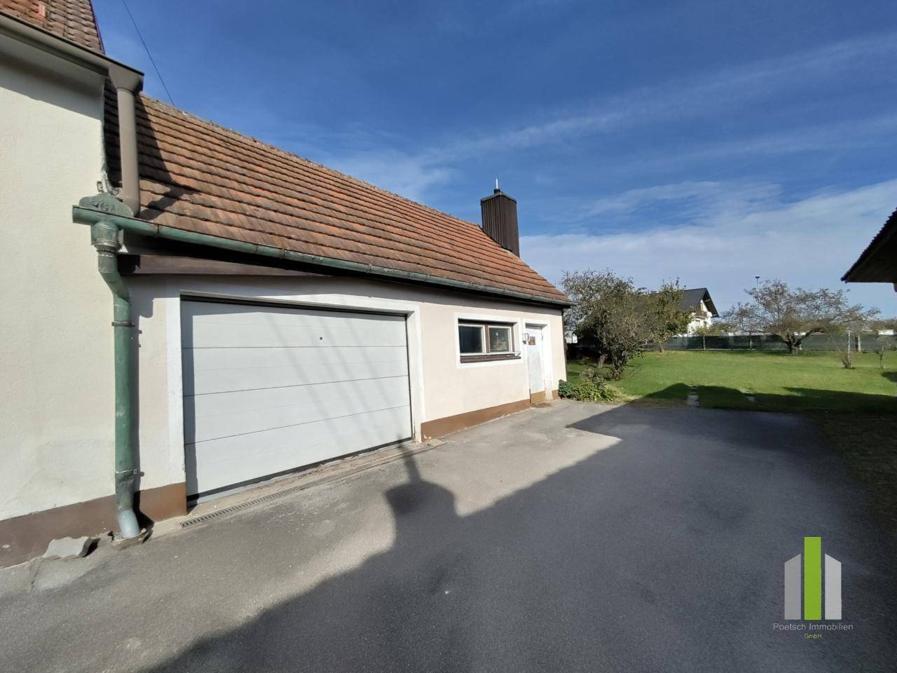 Einzelgarage mit weißem Garagentor und Zufahrt neben dem Wohnhaus.