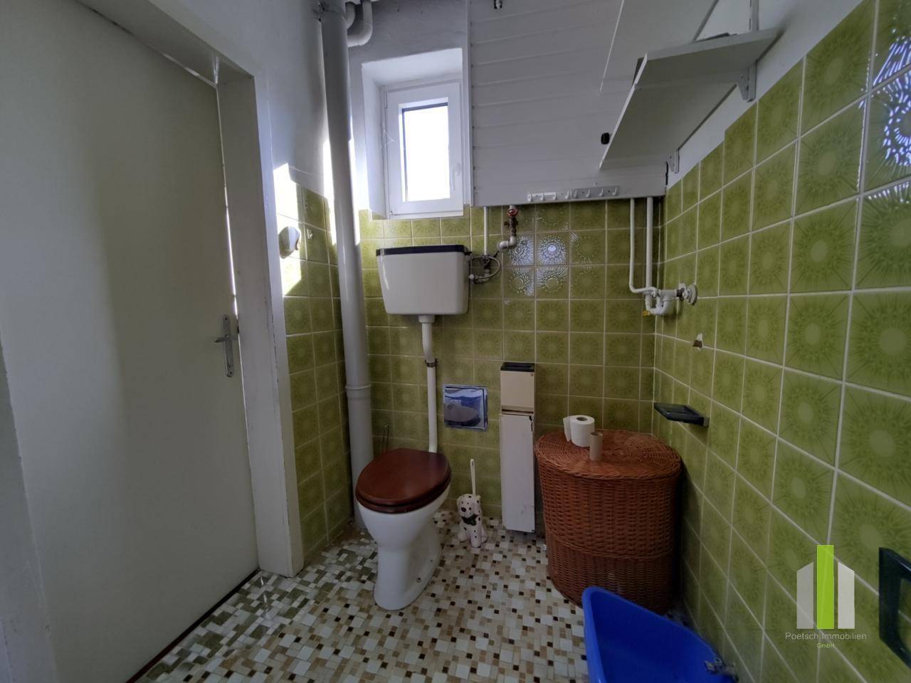 Kleines Gäste-WC mit grünen Fliesen, Fenster und traditioneller Toilette.