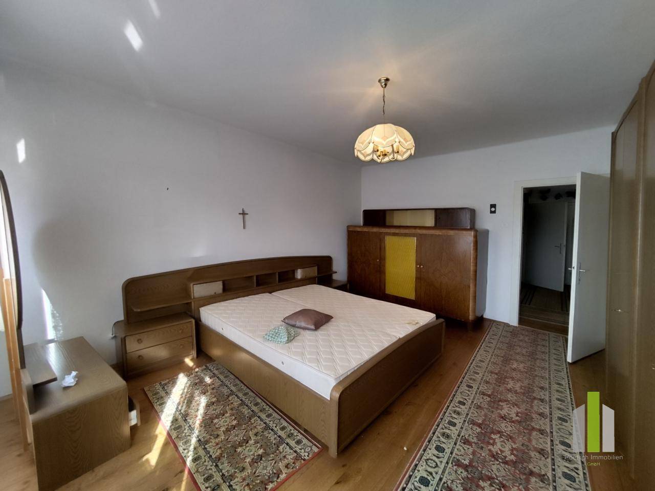 Geräumiges Schlafzimmer mit Doppelbett, Holzmöbeln und Parkettboden.