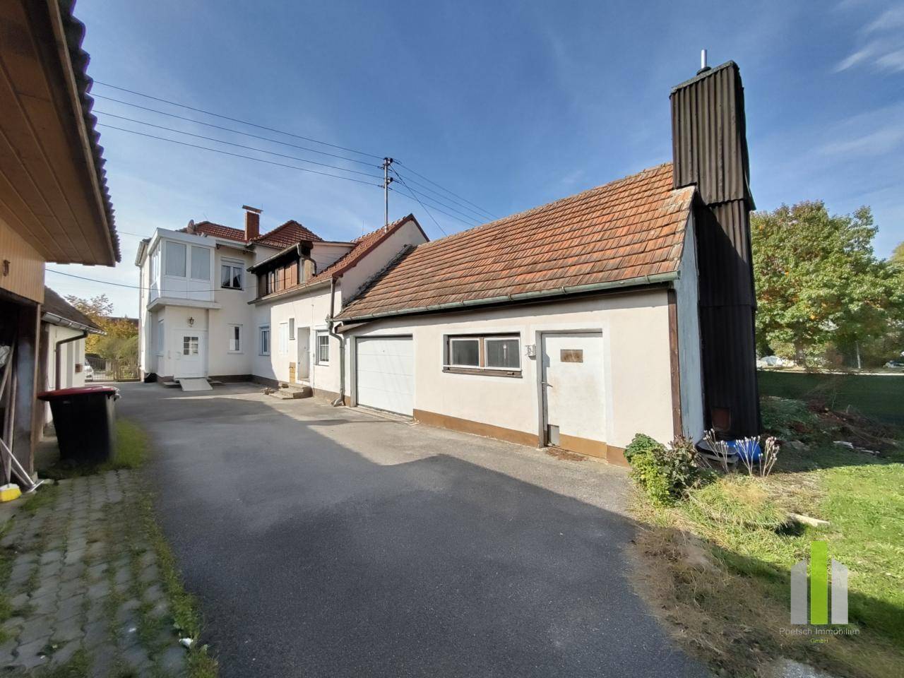 Seitenansicht des Hauses mit Garage, Zufahrt und Zugang zum Gartenbereich.