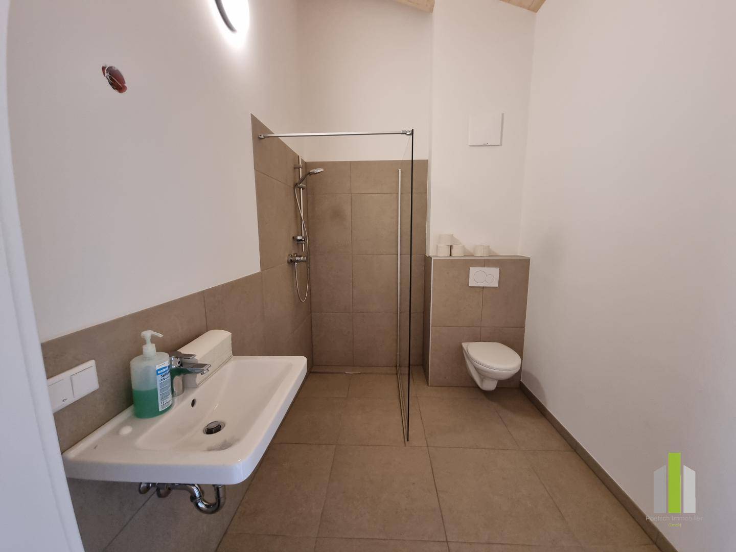Unfertiges Badezimmer mit begehbarer Dusche, WC und Waschbecken, bereit für die Fertigstellung.