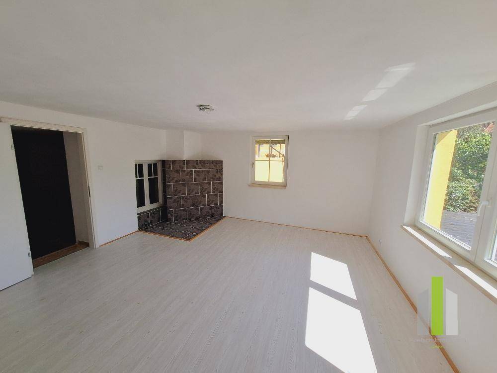 Helles, leeres Zimmer mit hellem Laminatboden und einem dekorativen Kaminbereich.