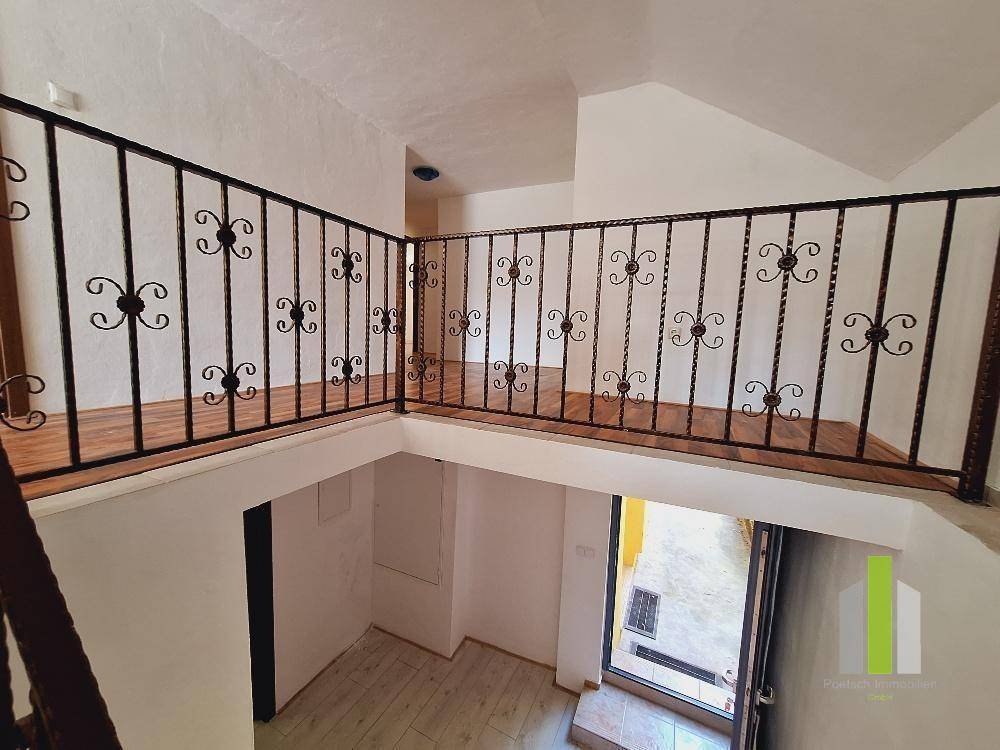 Obere Etage mit schmiedeeisernem Geländer und Blick auf den Eingangsbereich.