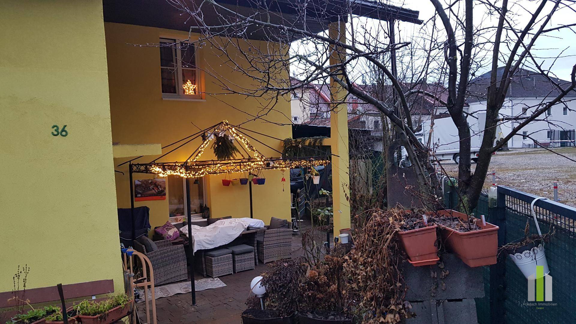 Gemütliche Terrasse mit Gartenmöbeln, festlicher Beleuchtung und Blick auf die Umgebung.