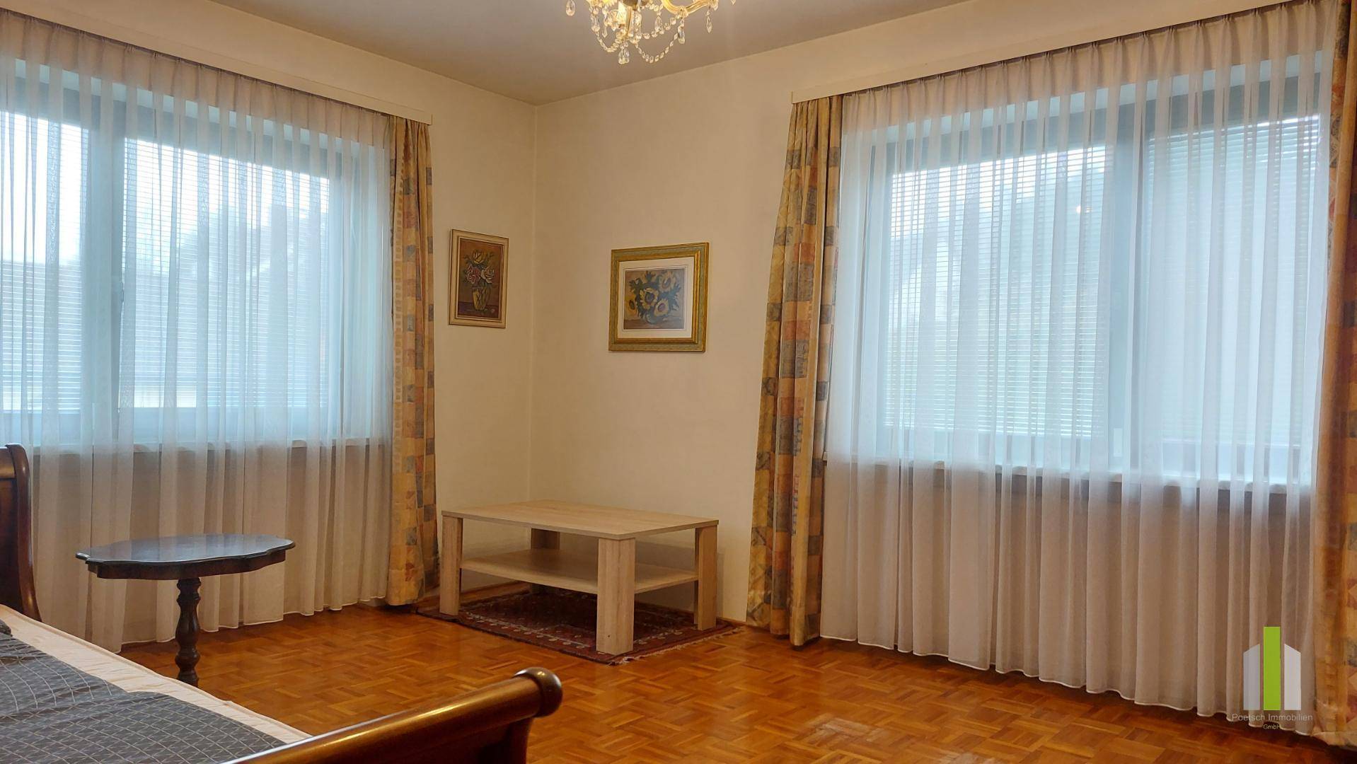 Schlafzimmer mit Parkettboden und großen Fenstern, die viel Tageslicht hereinlassen.