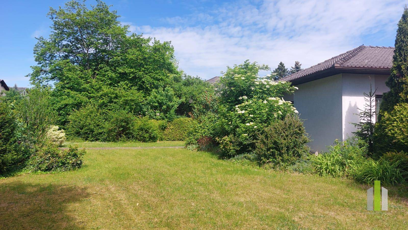 Weitläufiger Gartenbereich mit gepflegtem Rasen und üppiger Bepflanzung rund um das Haus.