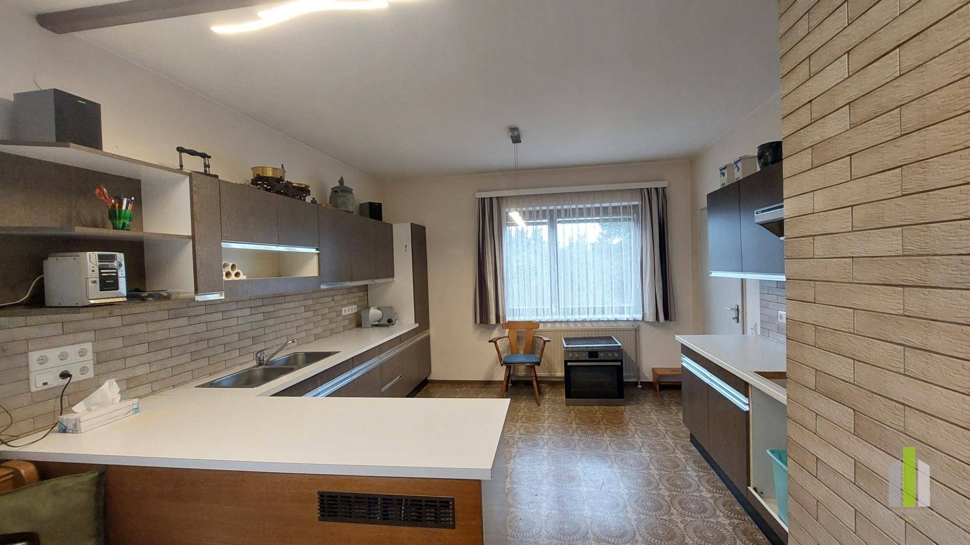 Funktionale Küche mit Einbauschränken, Arbeitsflächen und einem Fenster für Tageslicht.