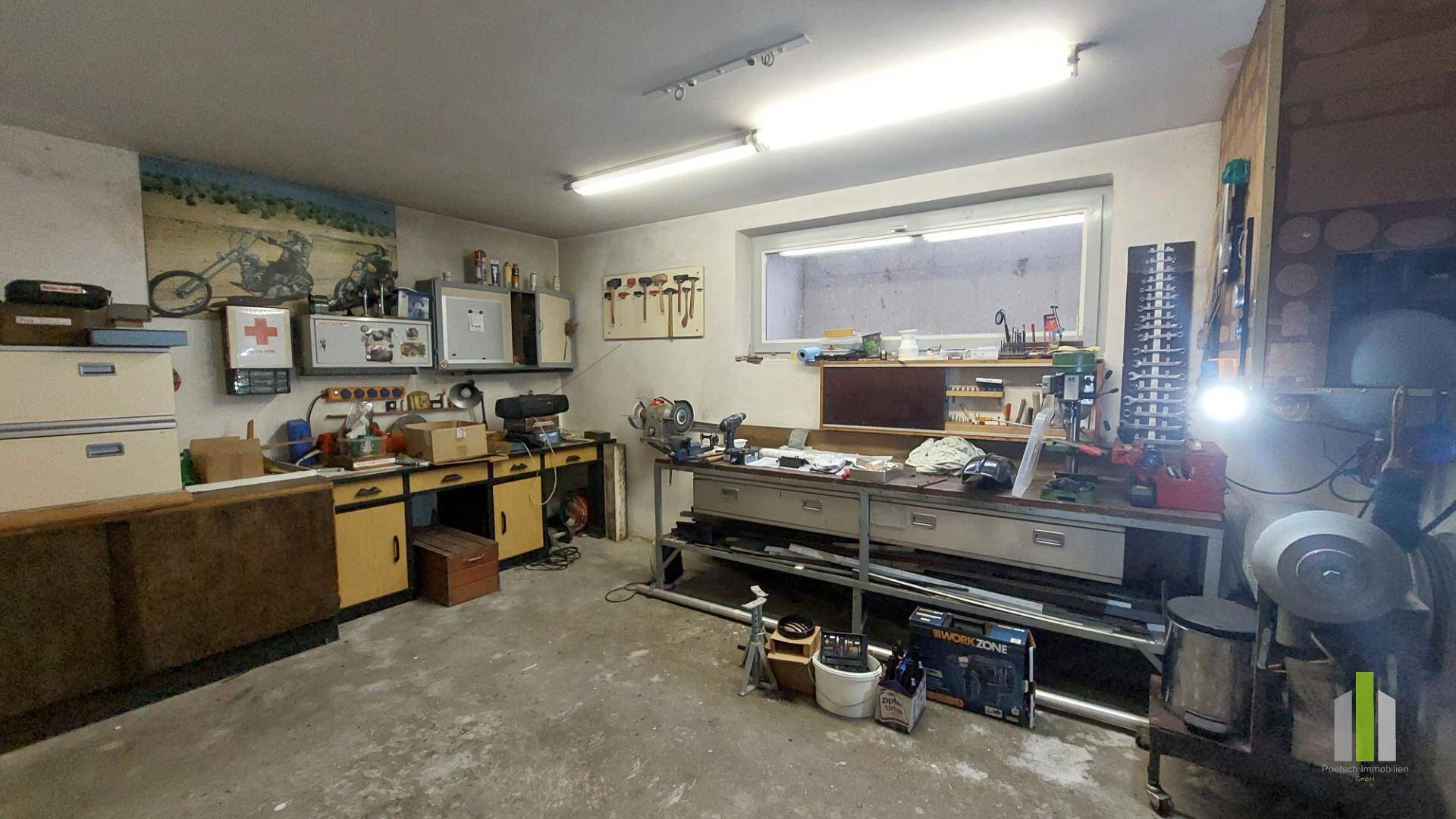 Geräumiger Hobbyraum oder Werkstatt im Untergeschoss mit großem Fenster und Arbeitsflächen.