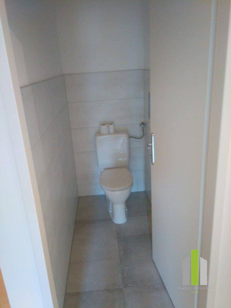 Separates WC mit Fliesenboden und einfacher Ausstattung.