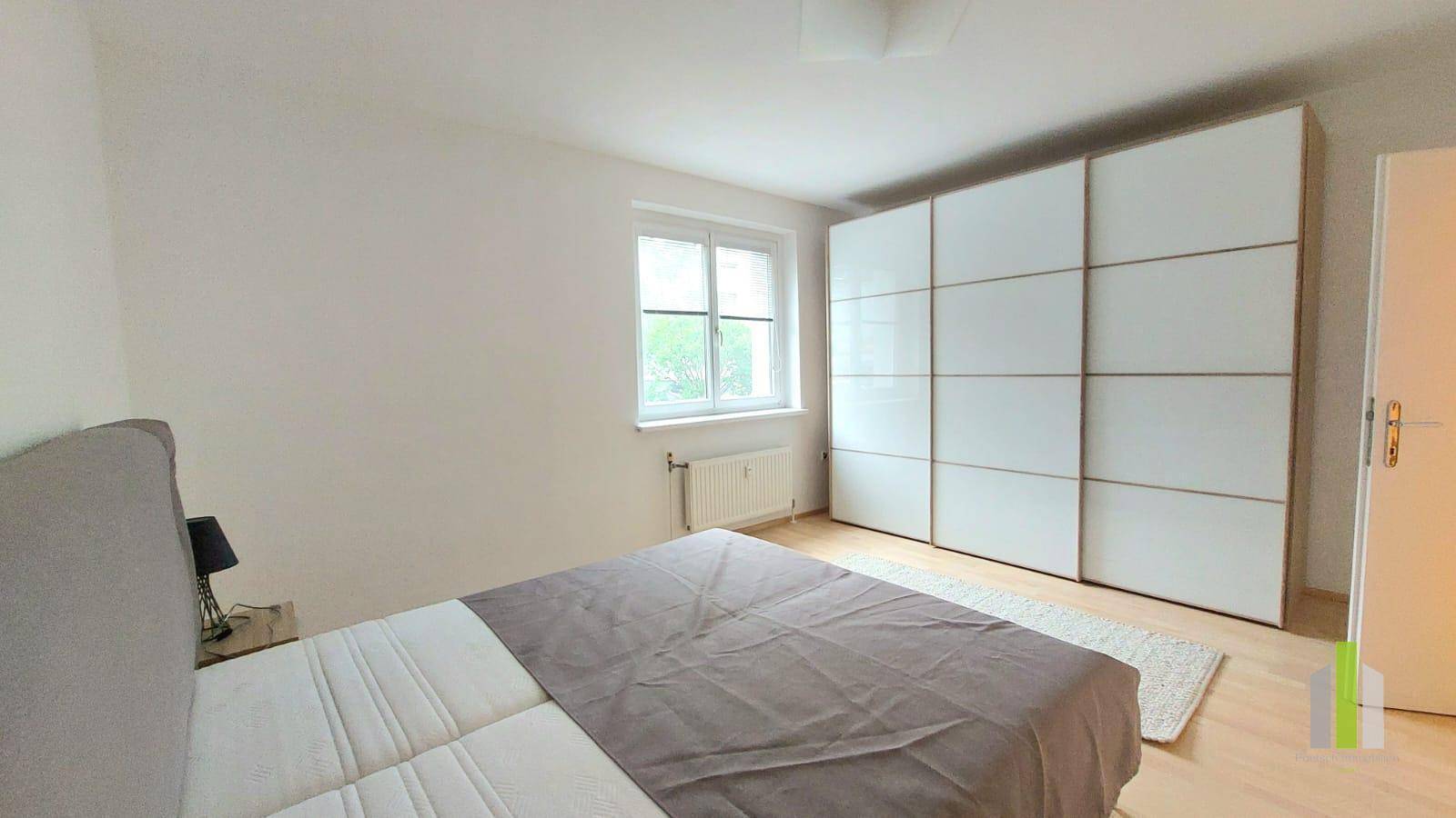 Helles Schlafzimmer mit großem Kleiderschrank und Blick nach draußen.