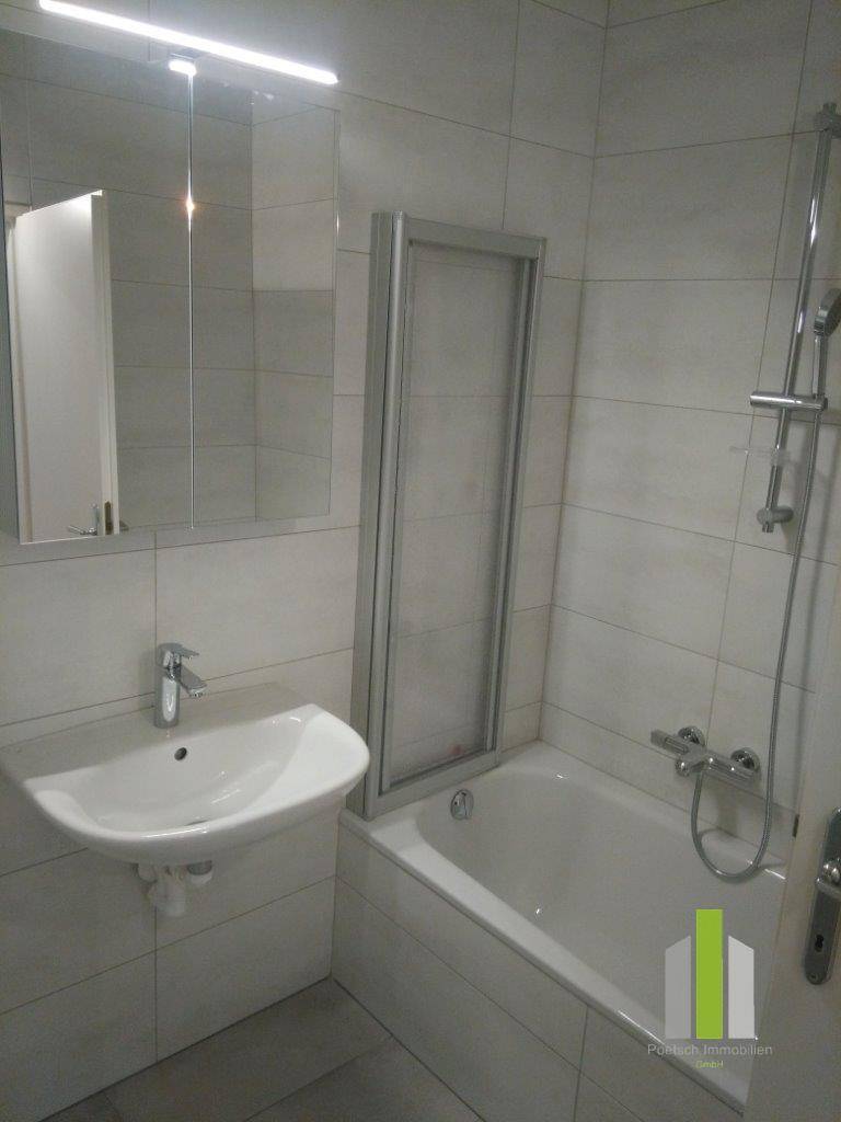 Modernes Badezimmer mit Badewanne, Duschwand, Waschbecken und Spiegelschrank.