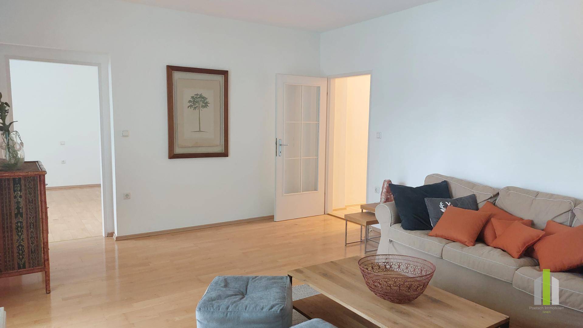 Geräumiges Wohnzimmer mit Parkettboden und Zugang zu weiteren Zimmern.