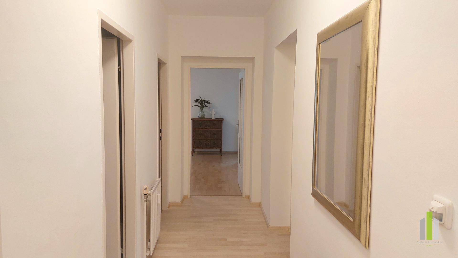 Langer, heller Flur mit Holzboden, der zu den verschiedenen Räumen führt.