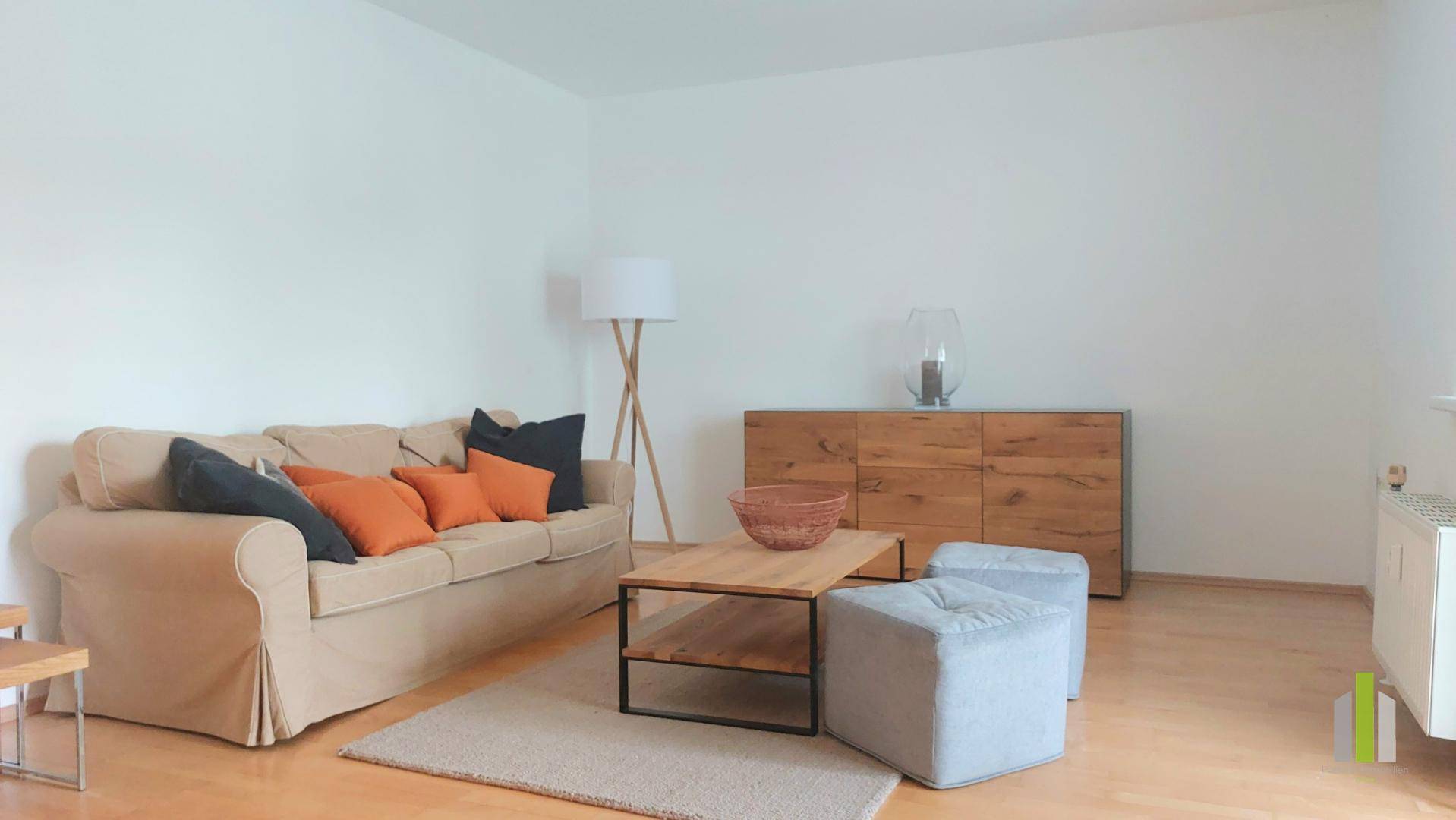 Heller Wohnbereich mit beiger Couch, Holzmöbeln und einem modernen Beistelltisch.